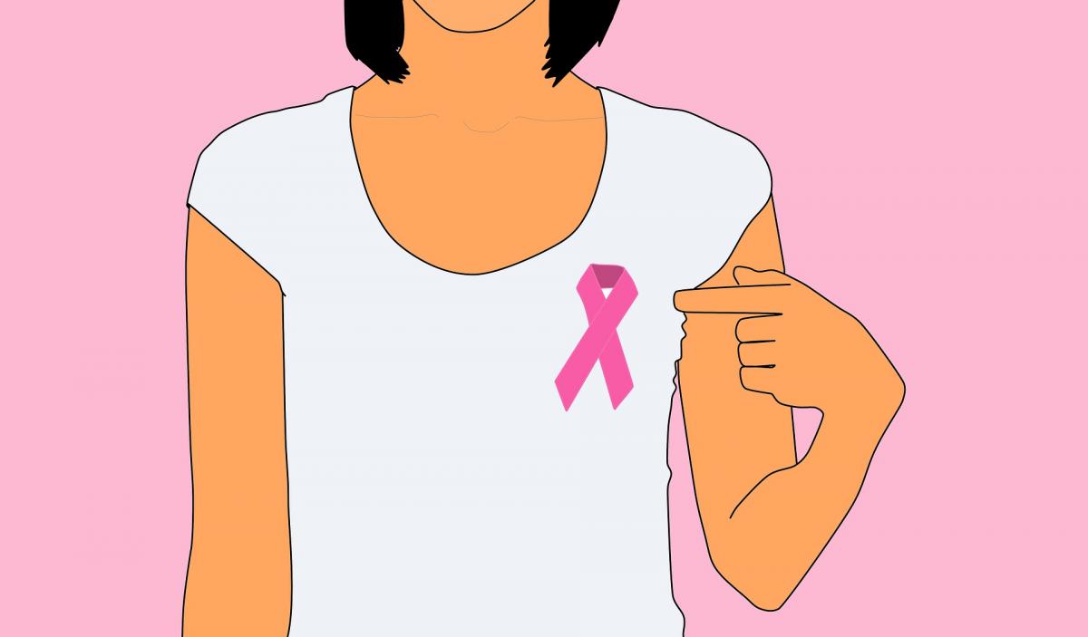 woman with breast cancer ribbon pointing to the ribbon